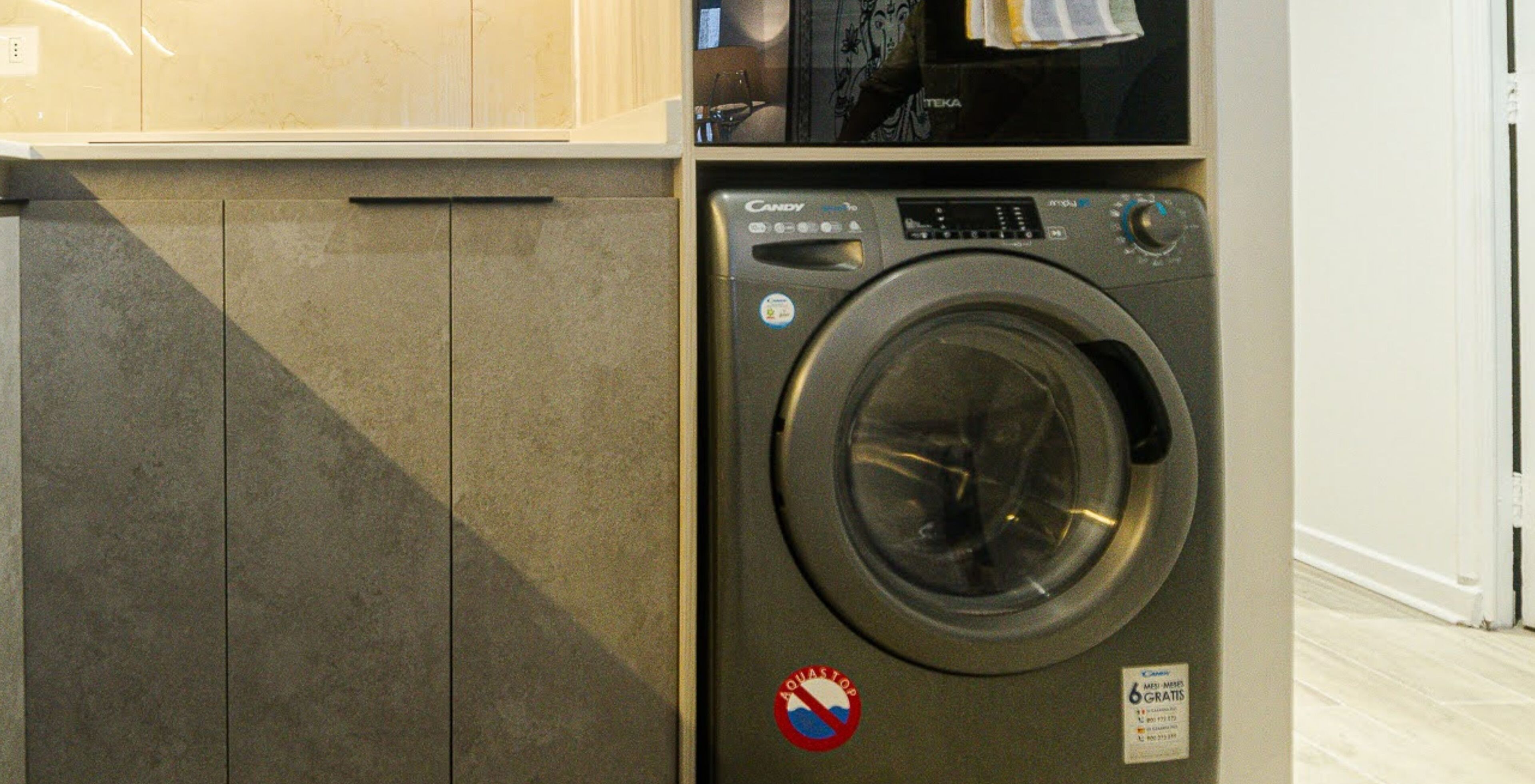 A front-loading washing machine with a control panel and a "QUASTOP" sticker.
