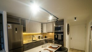 Uma cozinha compacta com geladeira embutida, micro-ondas, forno e pia.