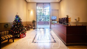 Um hall de entrada com uma árvore de Natal, uma receção e uma escadaria que leva a uma área externa.