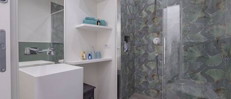 A modern bathroom with a glass shower enclosure, a white sink, and a mirror.
