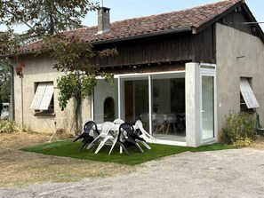 A modern house with a patio, a dining area with chairs, and a large sliding glass door. - En Vayssières - Albiac (Albiac)