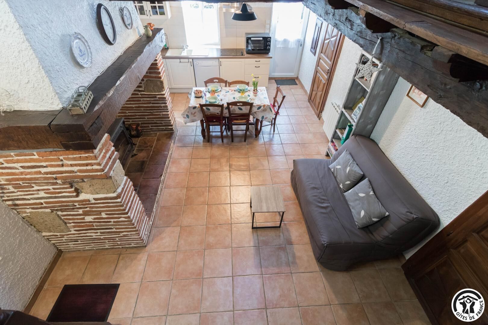 A cozy kitchen with a dining area, a fireplace, and a sofa.