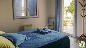 A bedroom with a bed, a chair, a window, and a view of the outdoors. - Gaoudens - Soueich - Gîte (Soueich)