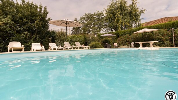 Una piscina con sillones de baño y sombrillas.