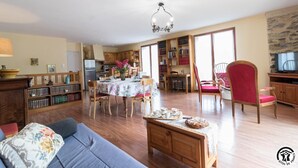 Una sala de estar acogedora con un sofá, una mesa de comedor preparada para tomar té, una estantería y una zona de cocina.