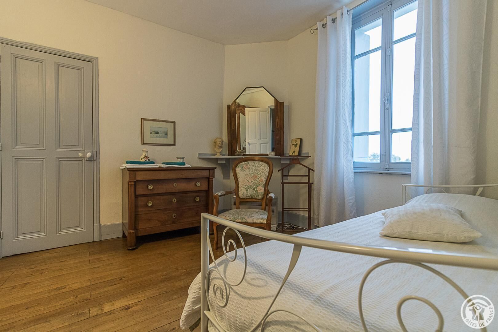 A bedroom with a bed, dresser, chair, and a mirror.