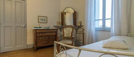 A bedroom with a bed, dresser, chair, and a mirror.