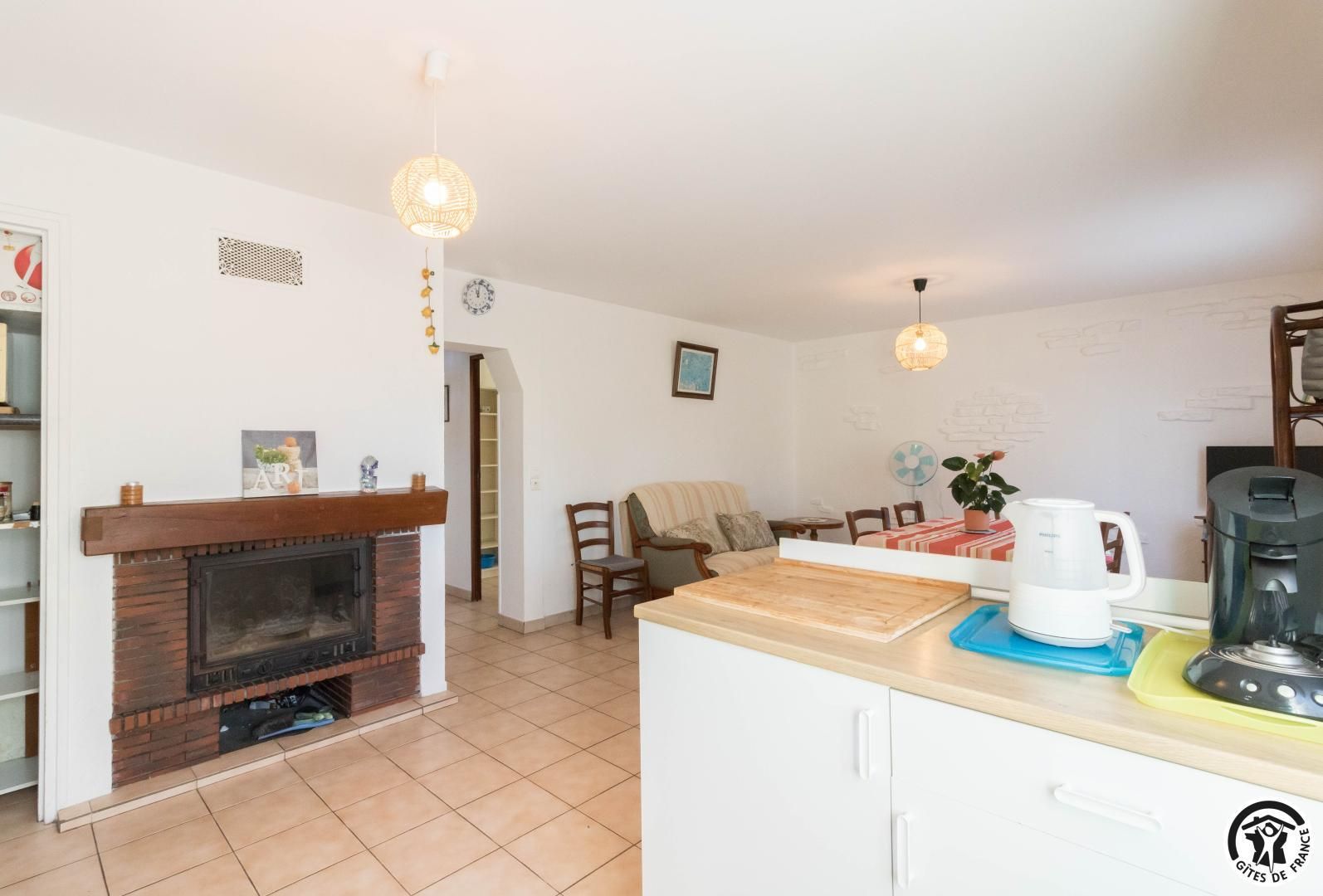 A modern kitchen with a built-in stove, a coffee maker, and a dining area with a table and chairs.