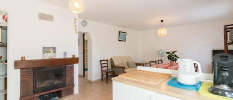 A modern kitchen with a built-in stove, a coffee maker, and a dining area with a table and chairs.