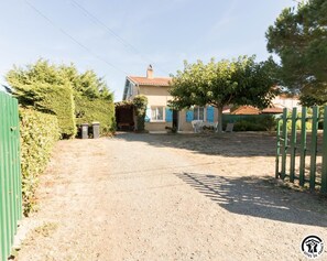 A residential property with a gravel driveway, a fenced yard, and a house with a red roof. - Le Pin Parasol - L'herm (Lherm)