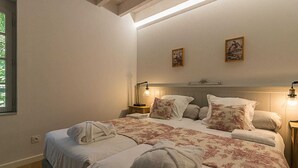 Un lit bien fait, avec une literie à motifs floraux et des serviettes assorties, une tête de lit agrémentée d’œuvres d’art mural et des lampes de chevet.