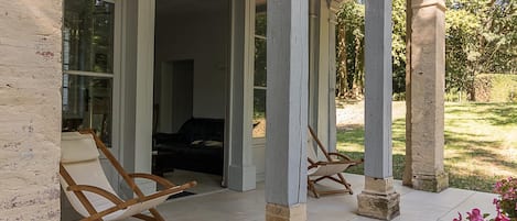 Overdekt terras met houten schommelstoelen en uitzicht op het interieur.