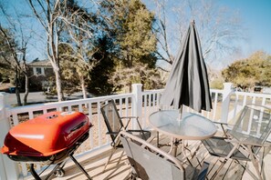 Um terraço com churrasqueira, mesa e cadeiras.