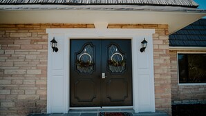Une porte à deux battants ornée de panneaux de verre décoratifs et un paillasson.