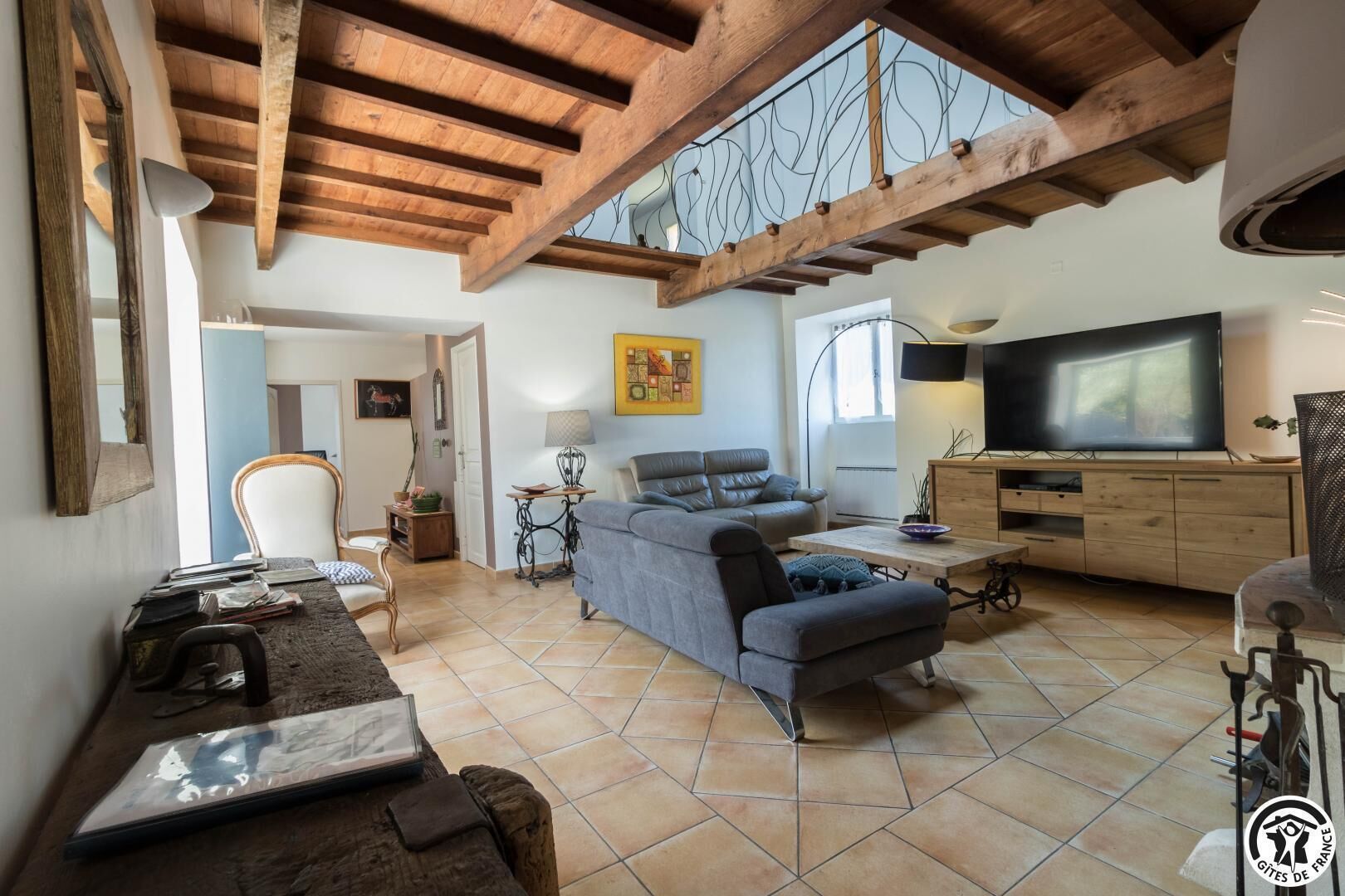 Een ruime woonkamer met een bank, een televisie en een houten plafond.
