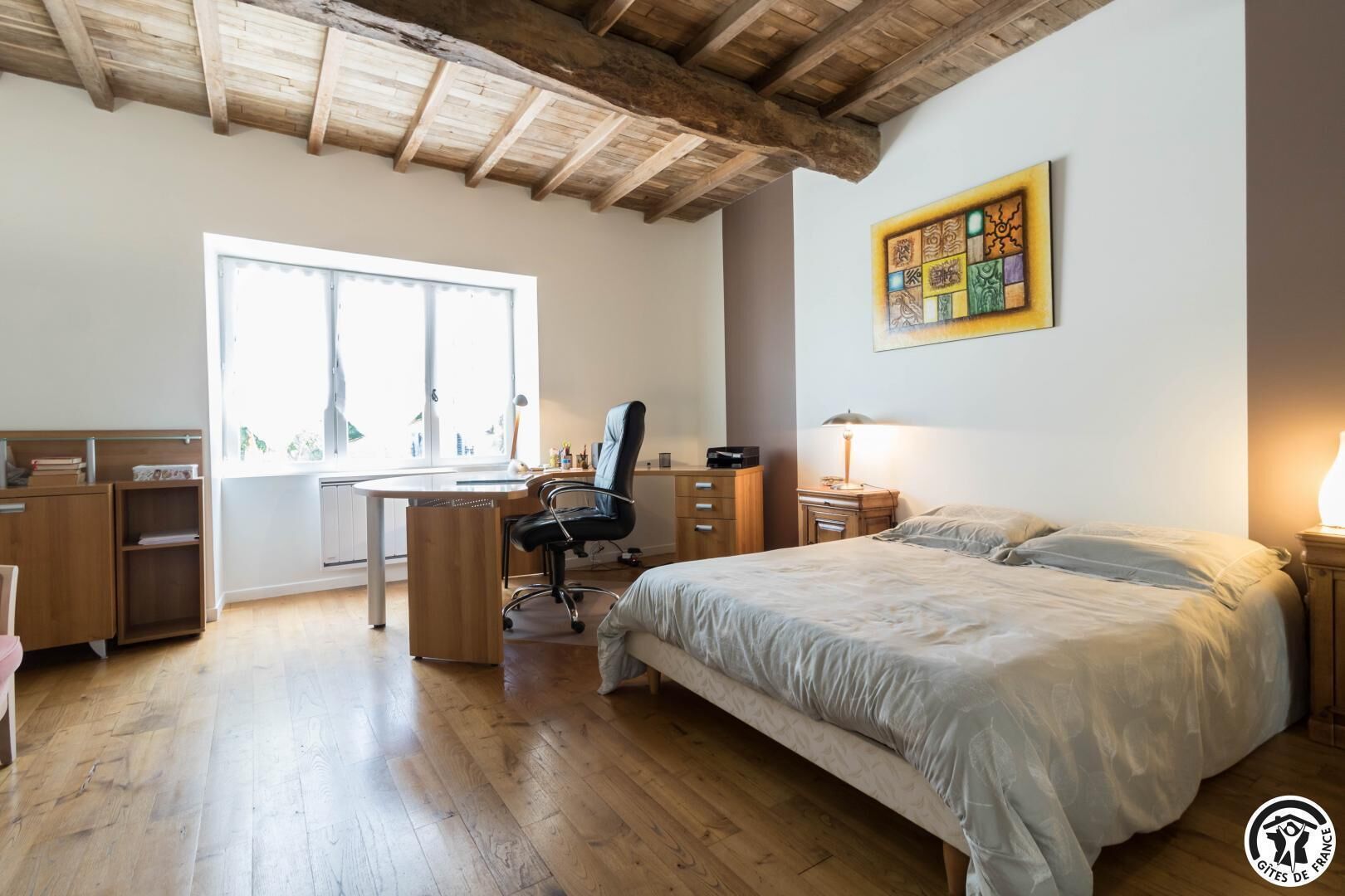 Ein Schlafzimmer mit Bett, Schreibtisch, Stuhl, Nachttisch und einem Fenster.