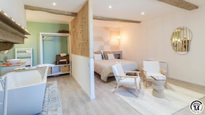 A bedroom with a bed, two chairs, a small table, a mirror, and a wardrobe.