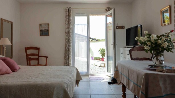 A bedroom with two beds, a television, a chair, and a window with curtains.