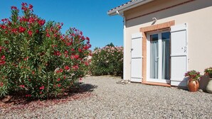 A building with a beige exterior, a white door, and a gravel driveway.