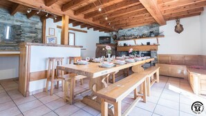 A rustic kitchen with wooden beams, stone walls, and a long dining table set for six. - Benque-Dessus Farm (Benque-Dessous-et-Dessus)