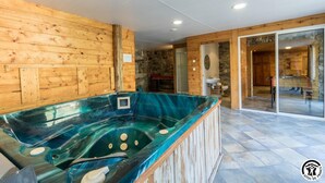 A spa area with a glass-enclosed hot tub, wooden walls, and a stone wall in the background. - Benque-Dessus Farm (Benque-Dessous-et-Dessus)