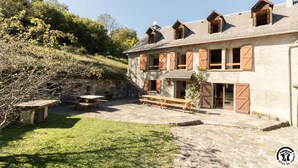 A rustic stone building with multiple windows and shutters, a stone bench, and a grassy courtyard. - Benque-Dessus Farm (Benque-Dessous-et-Dessus)