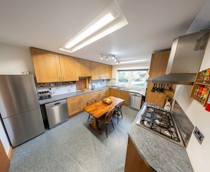 A modern kitchen with stainless steel appliances, wooden cabinets, a granite countertop, and a dining area with a wooden table and chairs. - Sahara!  House with Sauna close to the beach (Rock)
