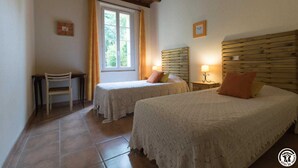 A room with two beds, a desk, and a window with curtains.