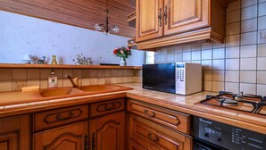 Une cuisine avec des meubles en bois, un évier en acier inoxydable, un four à micro-ondes et une cuisinière à gaz.