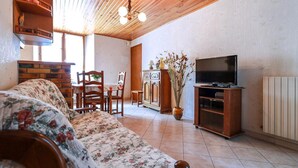 Un salon chaleureux avec un plafond en bois, un canapé, un meuble pour la télévision et un coin repas.