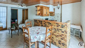 Une cuisine chaleureuse avec des meubles en bois, un mur d’accent en briques et un coin repas comprenant une table et des chaises.