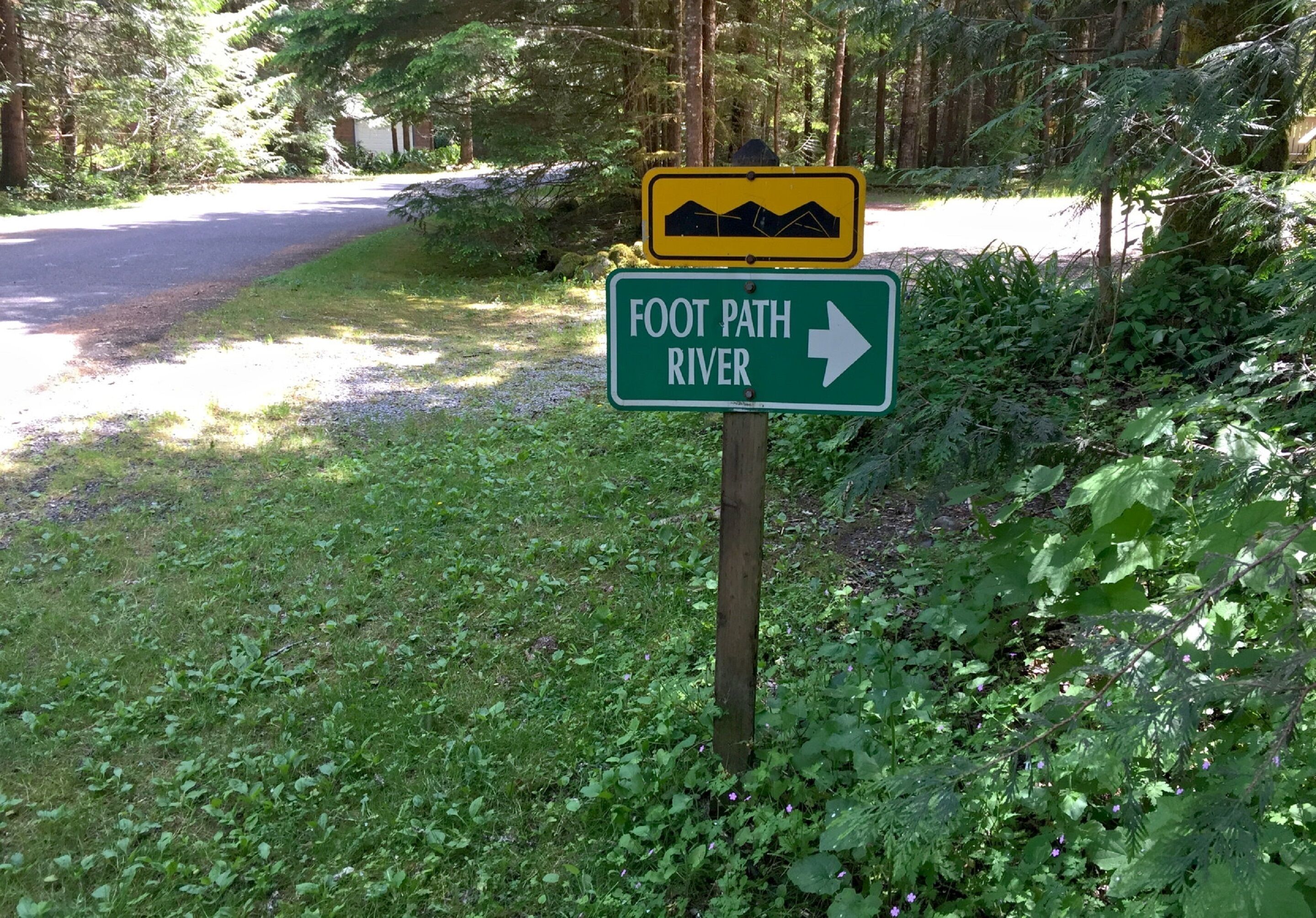 A sign indicating a footpath to River with a mountain symbol.