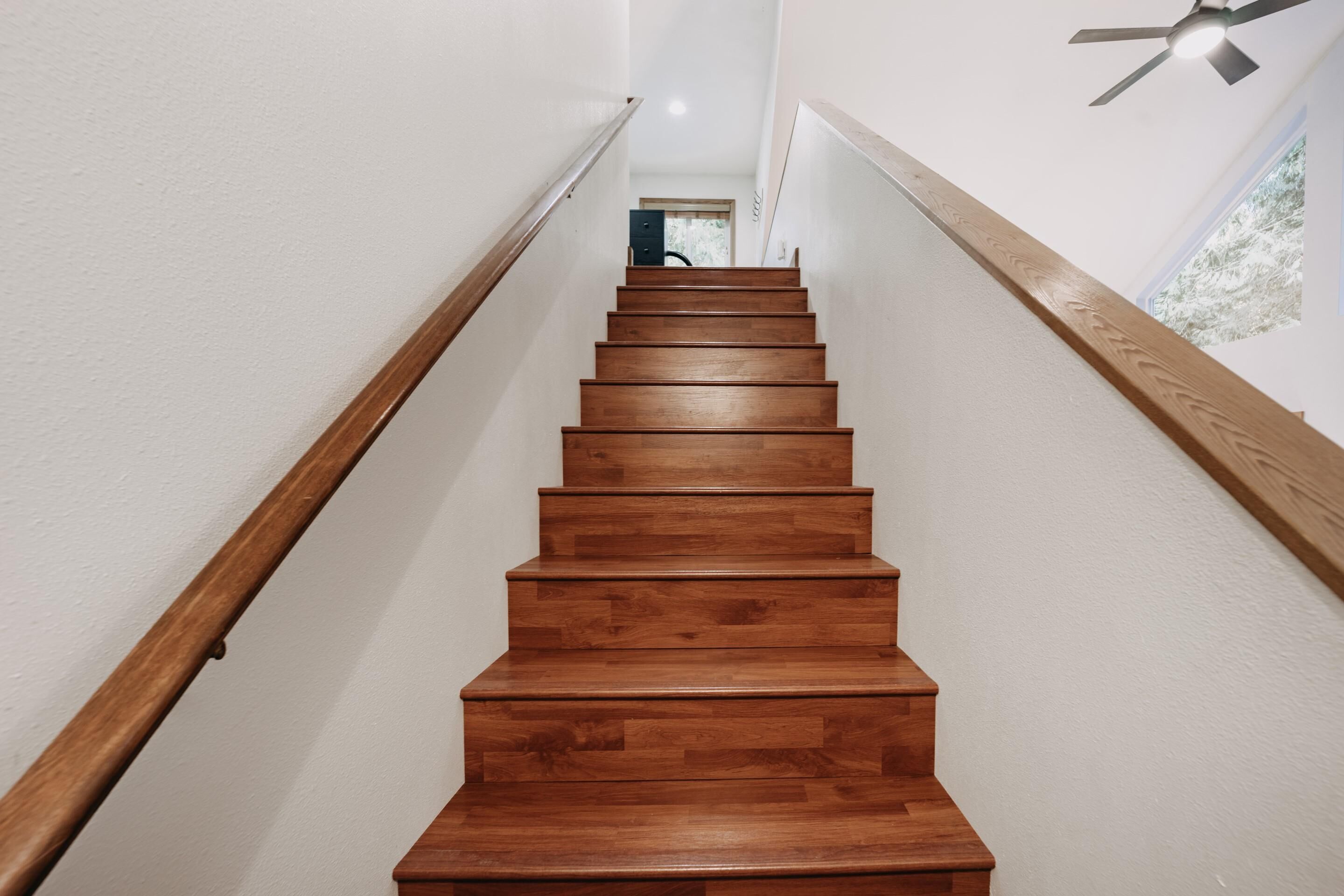Un escalier en bois, doté d’une rampe de chaque côté, qui mène à une porte située en haut.