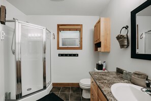 A bathroom with a glass-enclosed shower, a toilet, a sink, and a window above the toilet. - Mt Baker Rim Cabin 24 - Hot Tub, Wifi, Air Conditioning, Sleeps 8 (Deming)