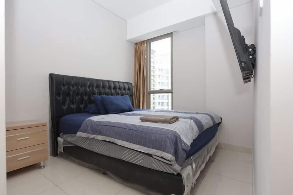 A bedroom with a bed, a nightstand, and a window.