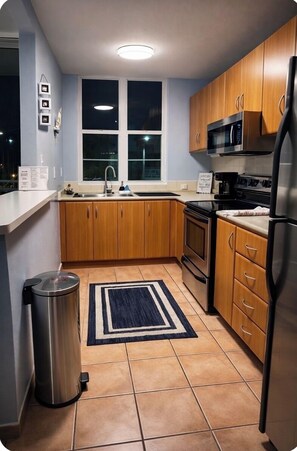 A kitchen with wooden cabinets, a stainless steel refrigerator, a microwave, and a stove.