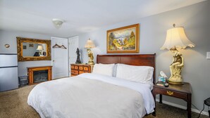 A hotel room with a large bed, a dresser, a mirror, a painting, and two lamps. - Americana Room. Elegant room with a King-Size bed, en suite bathroom, and mountain views. Sleeps 2. <br>A gourmet breakfast is FREE and served fresh each morning.<br>Americana Room is located on the second floor of Mountain Treasure Bed and Breakfast (Maplecrest)