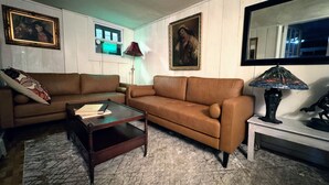 A living room with two brown sofas, a coffee table, a lamp, and framed artwork on the walls. - Art Nouveau Room<br>Large room decorated in the Art Nouveau style with FULL-size bed, en suite bathroom.FREE breakfast. Sleeps 2. (Maplecrest)