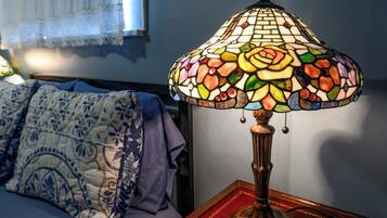 Una habitación con una cama, una mesita de noche con lámpara y una ventana con cortinas.