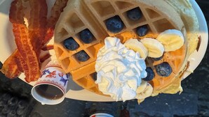 A plate with waffles, bacon, blueberries, banana slices, whipped cream, and syrup. - Fiddler On The Roof Room<br>Room with mountain views, a King-Size bed, en suite bathroom, and FREE breakfast. It sleeps 2. (Maplecrest)