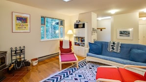A living room with a blue sofa, a red chair, a patterned rug, a fireplace, and a skylight.