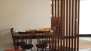 A dining area with a wooden table and chairs, a woven basket, and a red chair in the foreground. - Quinta Vila Rachel (Alijó)