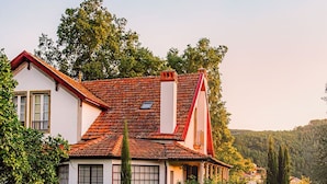 A traditional house with a red-tiled roof, white walls, and a cobblestone pathway leading to it. - Quinta Vila Rachel (Alijó)