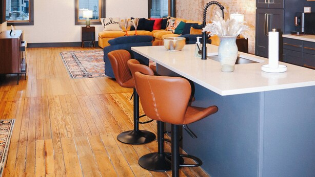 A modern kitchen with a central island, bar stools, and a seating area with a sofa and chairs. - Boujee on Third: 2-bedroom condo in Beautiful Downtown Marion  (Marion)