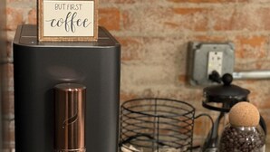 A coffee machine with a sign that reads "BUT FIRST coffee" on a kitchen counter. - Boujee on Third: 2-bedroom condo in Beautiful Downtown Marion  (Marion)