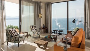 A spacious living room with a large window offering a view of the sea, a sofa, a chair, and a coffee table. - Villa Peninsula, Luxury accommodation with breathtaking Sea and Mountain views  (Plaka)