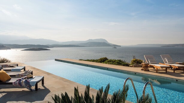 A poolside area with lounge chairs and a view of the sea. - Villa Peninsula, Luxury accommodation with breathtaking Sea and Mountain views  (Plaka)