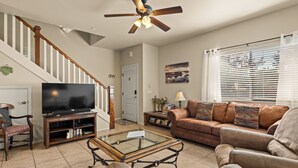 A living room with a TV, sofa, coffee table, and a staircase. - Bell Rock Vista - Hot Tub, Spacious Townhouse with Great Location and Views (Sedona)