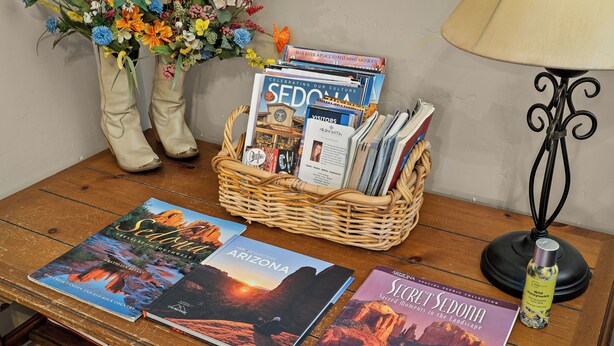 A wooden table with a wicker basket containing travel magazines, a pair of boots, and a lamp. - Bell Rock Vista - Hot Tub, Spacious Townhouse with Great Location and Views (Sedona)
