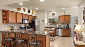 A kitchen with wooden cabinets, stainless steel appliances, a central island with bar stools, and a window with a view. - Bell Rock Vista - Hot Tub, Spacious Townhouse with Great Location and Views (Sedona)